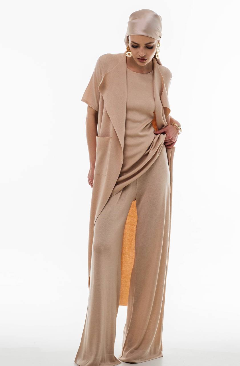 Woman wearing flowing sleeveless beige vest layered over wide-leg pants and top from Viamaro