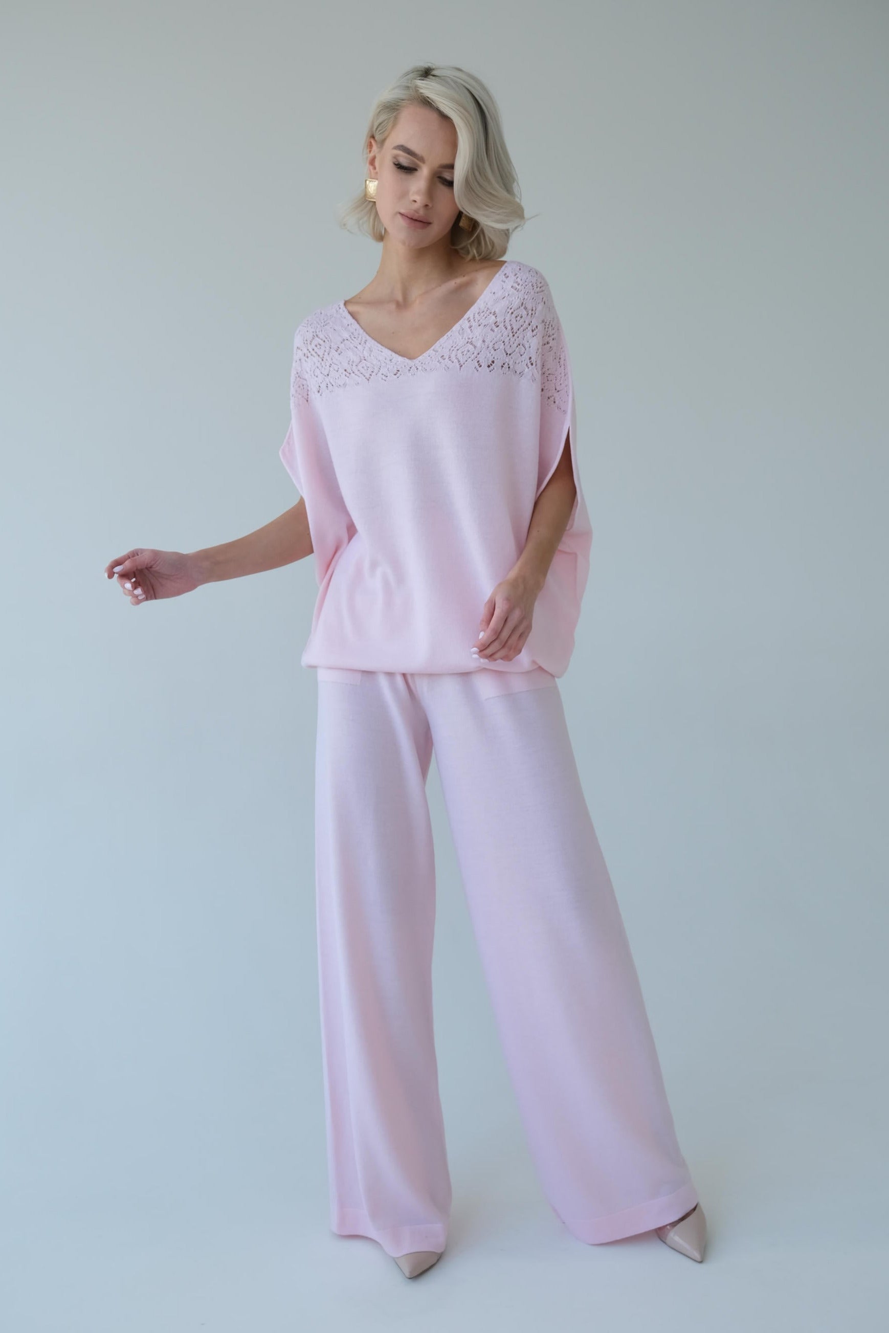 Woman wearing a pink outfit with lace details on a white background