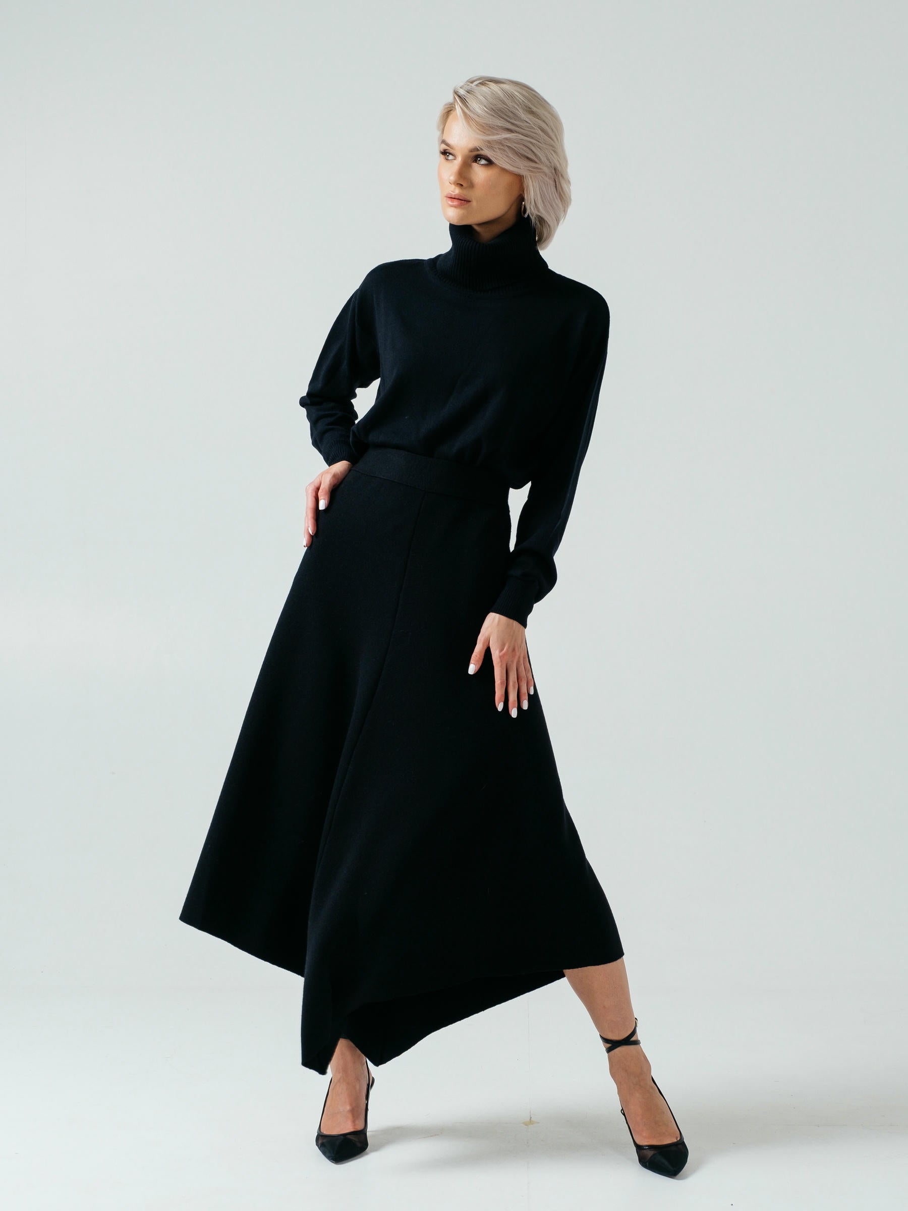 Woman wearing a black turtleneck and long skirt on a white background