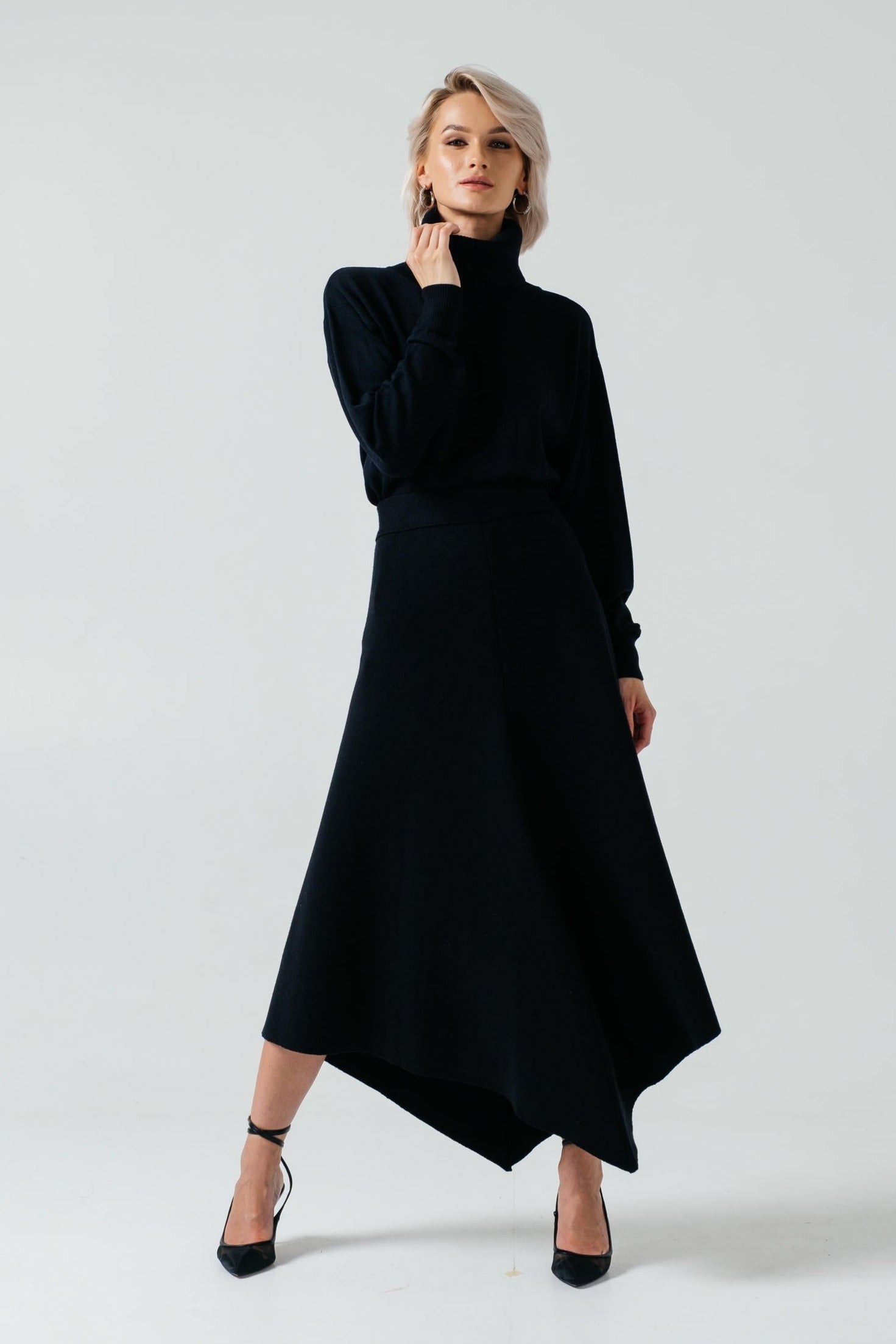 Woman wearing a black turtleneck and black skirt on a white background