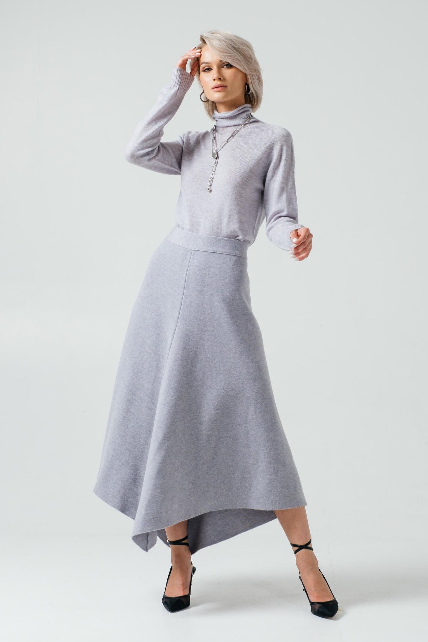 Woman wearing a gray outfit with a long skirt on a white background