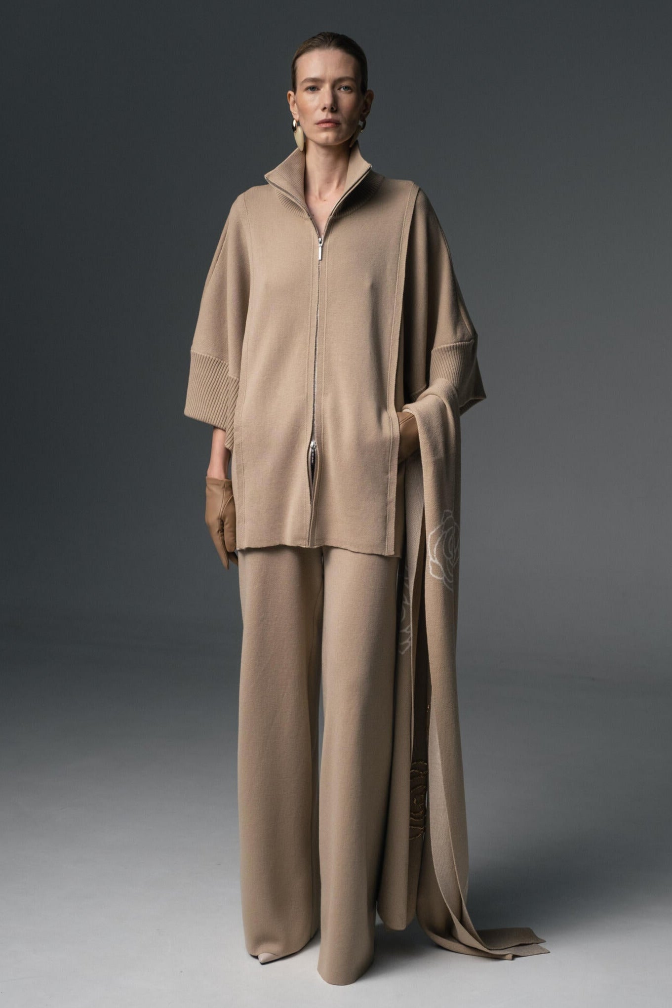 A pair of beige, wide-leg merino wool trousers with no visible pockets, displayed against a plain background.
