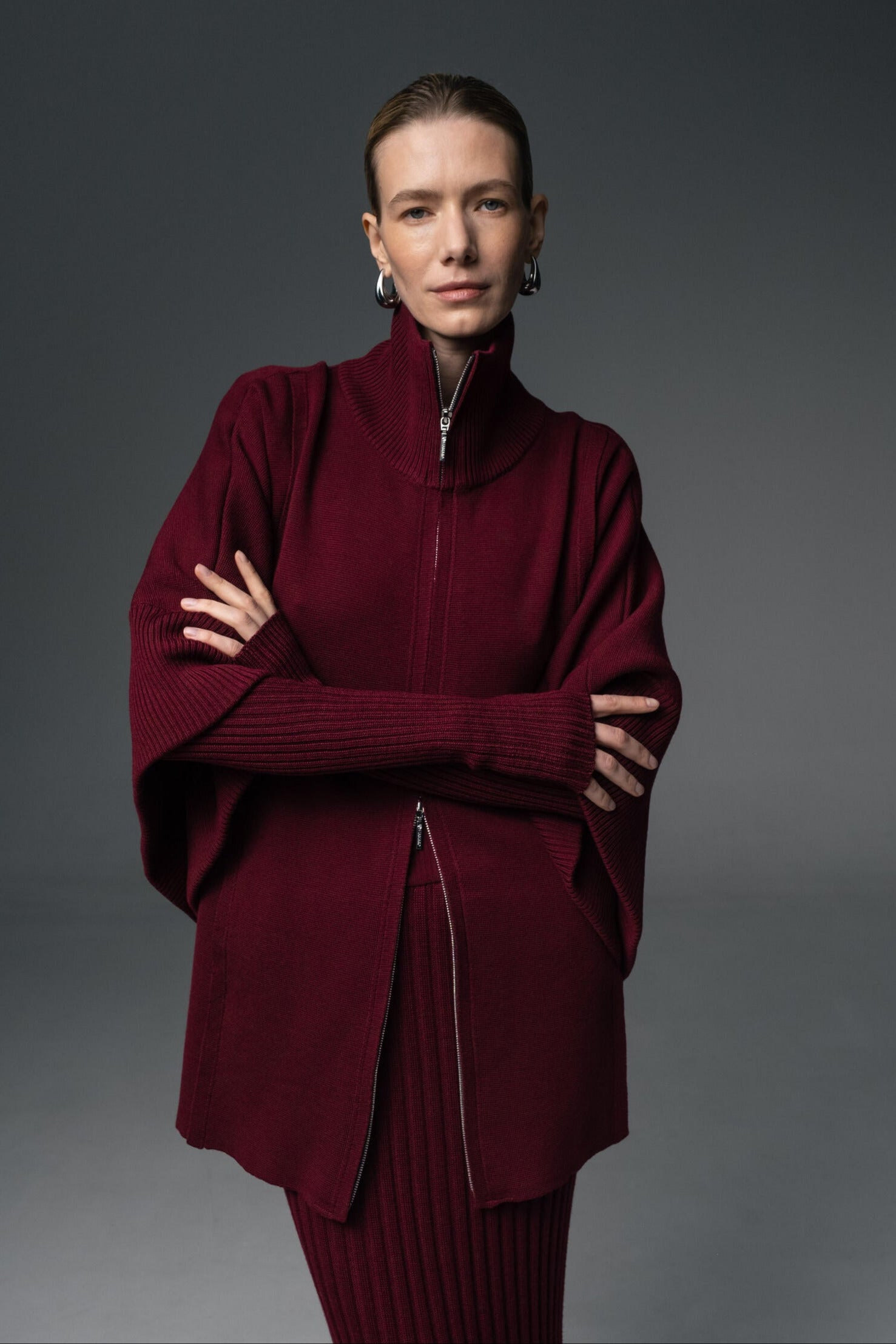A person wearing a double zip-up jogger set in burgundy color, consisting of a relaxed zip-up jacket and tapered joggers.