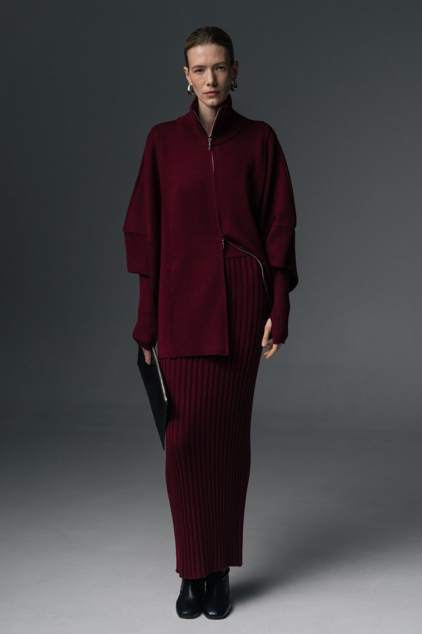 Person wearing a burgundy outfit against a gray background