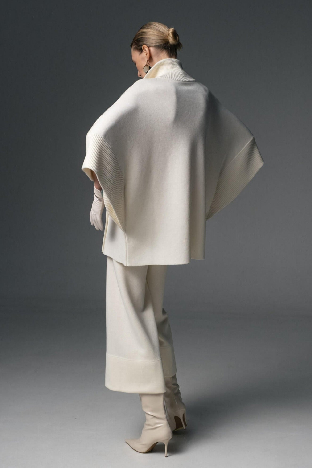 Person wearing a white coat and pants against a gray background