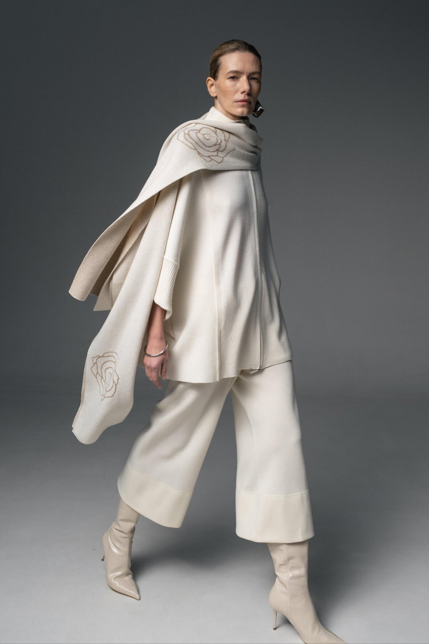 Person wearing a white outfit with a cape on a gray background