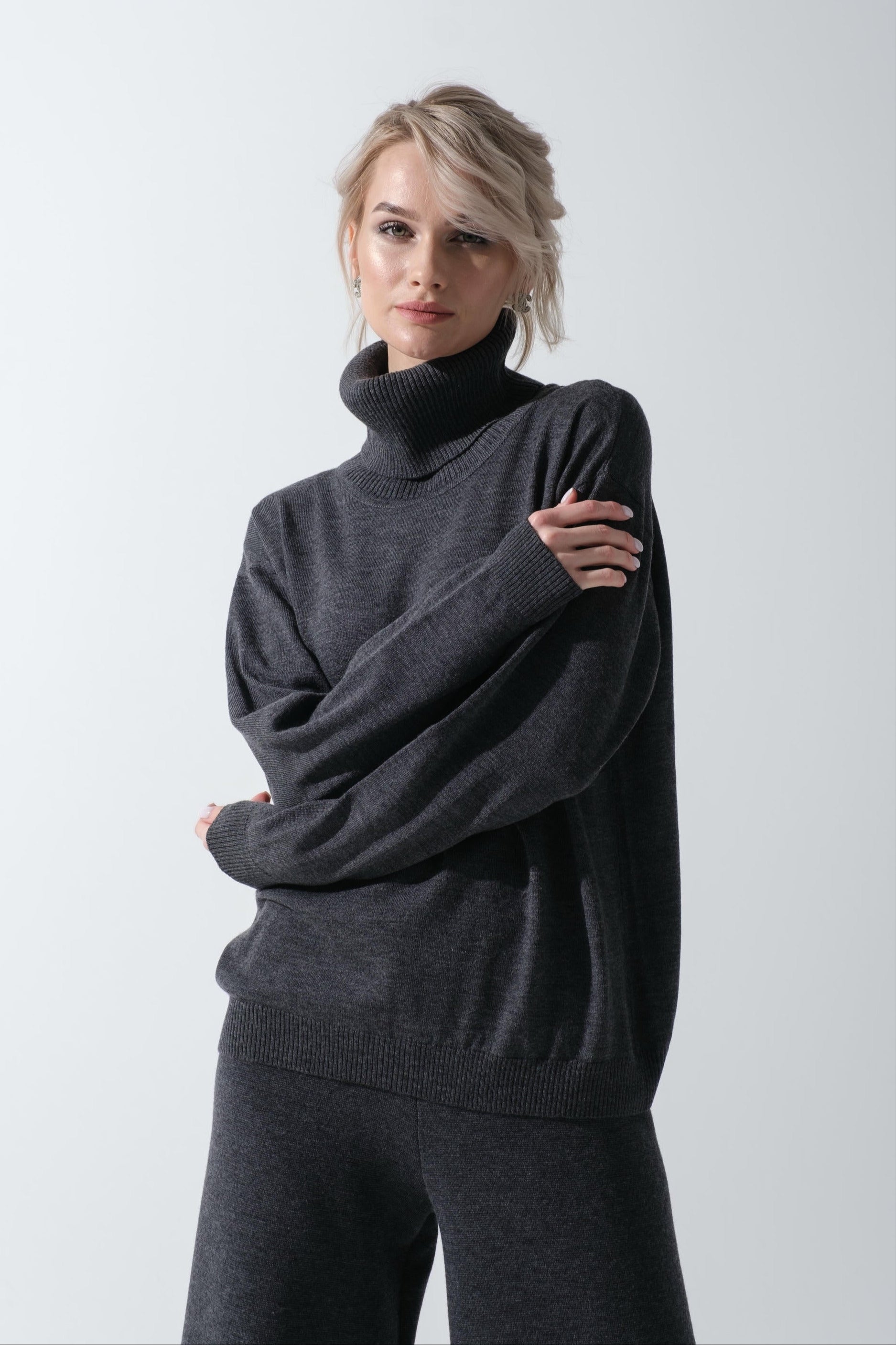 Woman wearing a dark gray sweater and pants on a white background