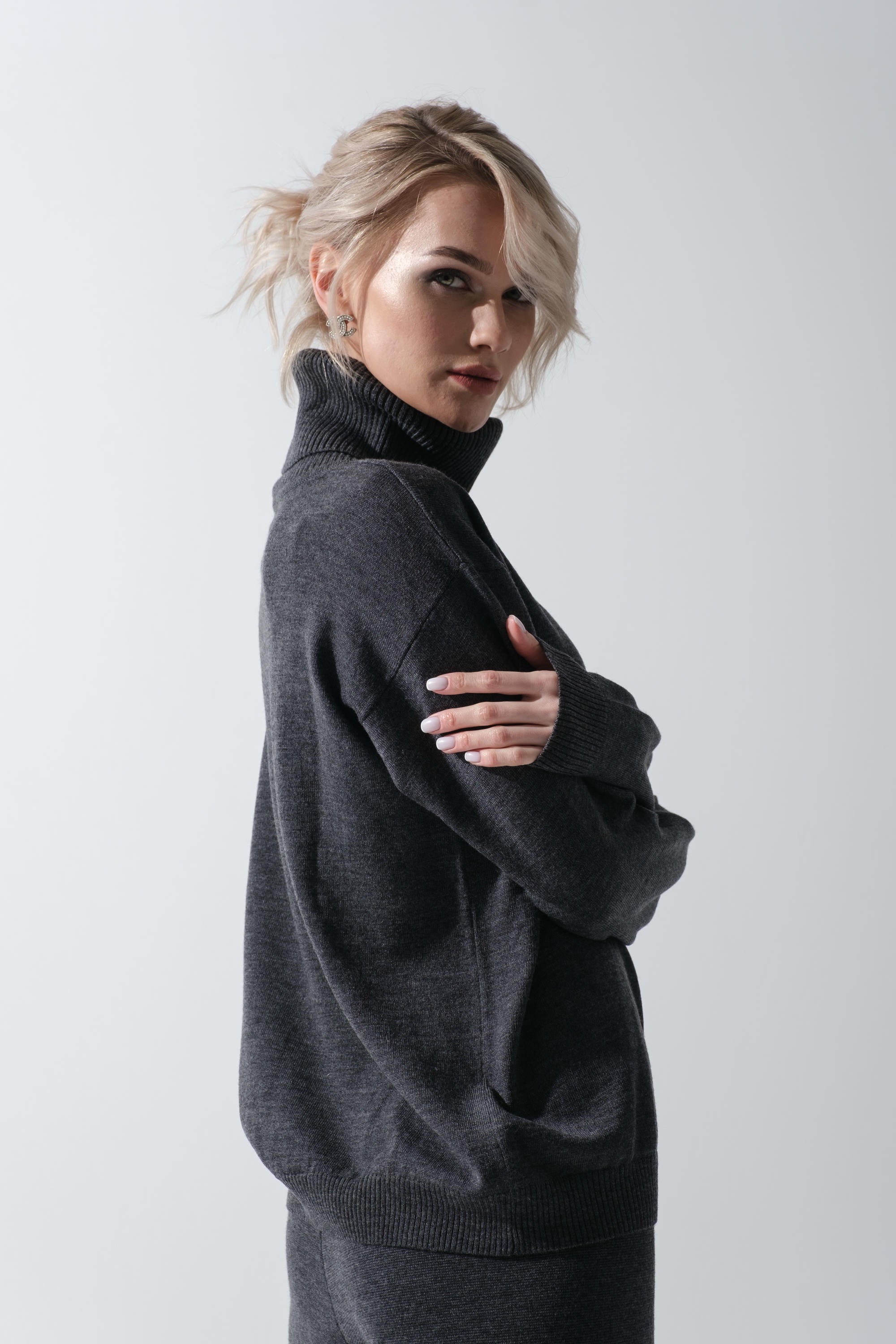 Woman wearing a dark gray turtleneck sweater against a light gray background