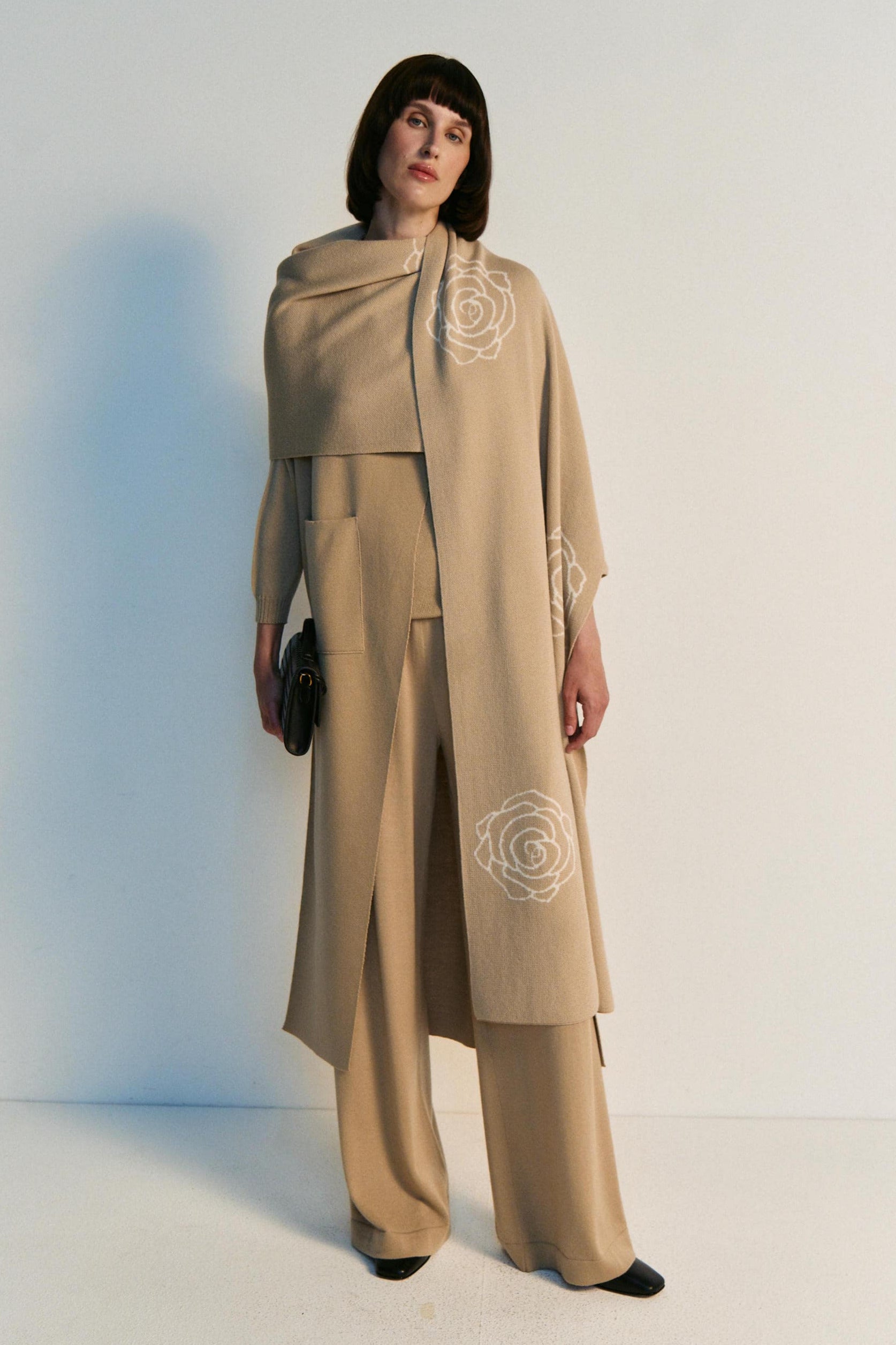 Woman wearing a beige outfit with floral embroidery on a white background