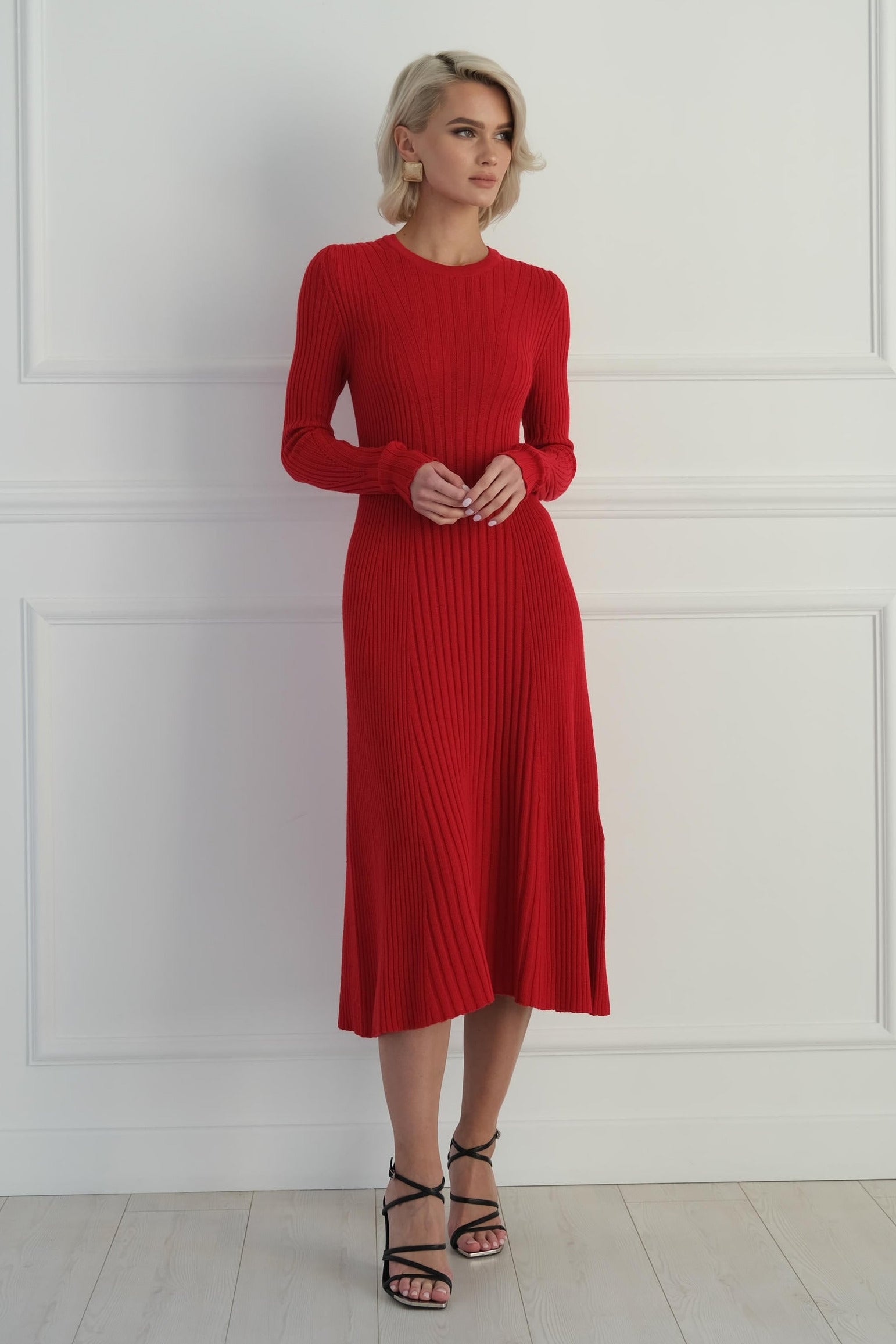 Woman wearing a red ribbed dress against a white wall