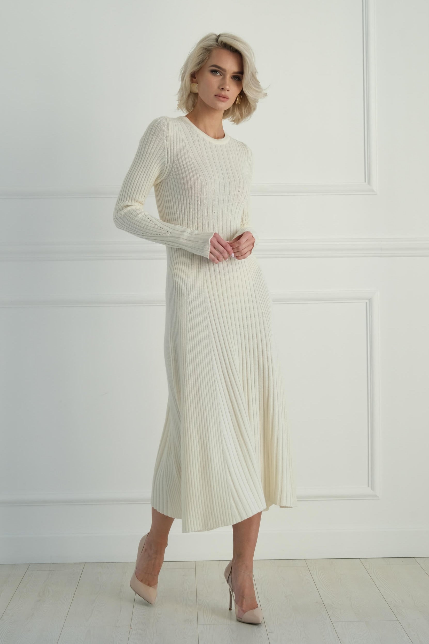 Woman wearing a white ribbed dress against a white wall
