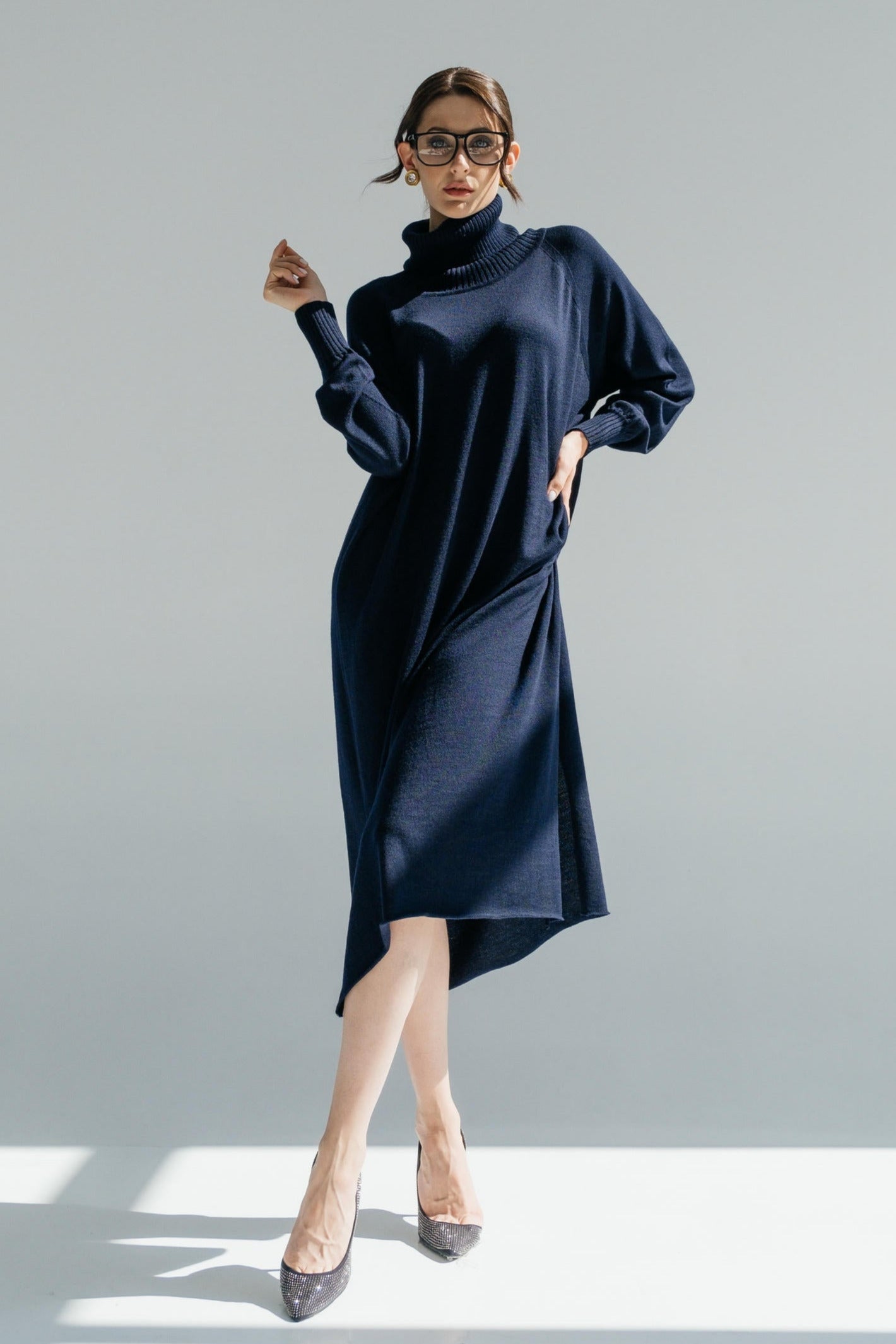 Woman wearing a dark blue dress with a high collar on a light gray background