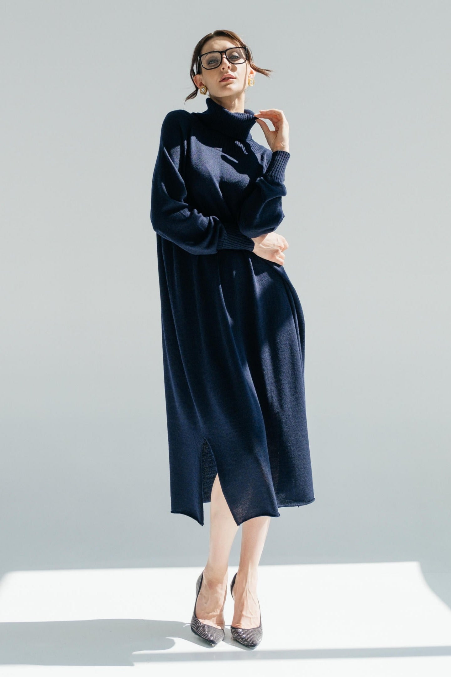 Woman wearing a navy blue dress and turtleneck against a white background