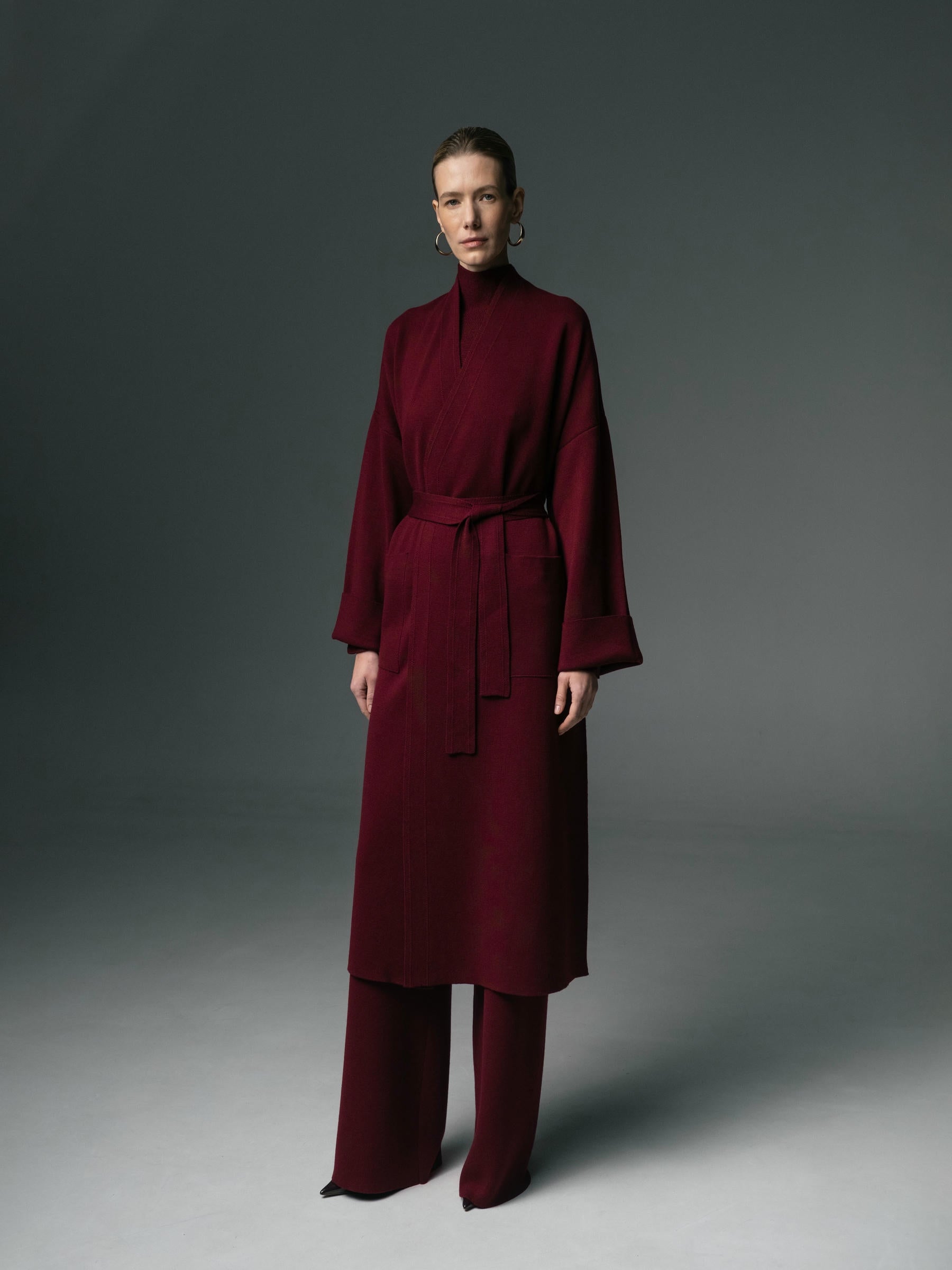 Person wearing a burgundy outfit against a gray background