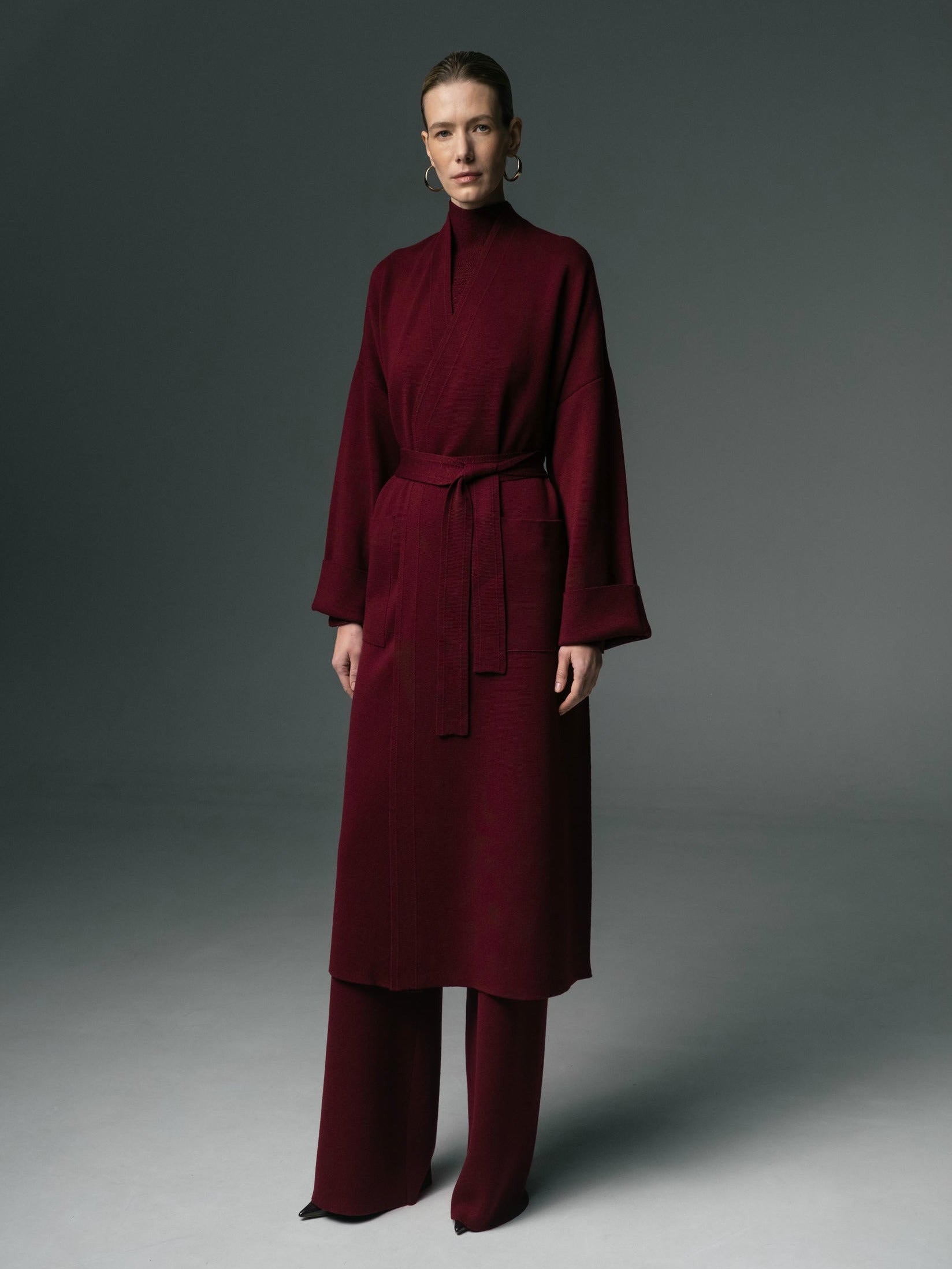 Person wearing a burgundy outfit against a gray background