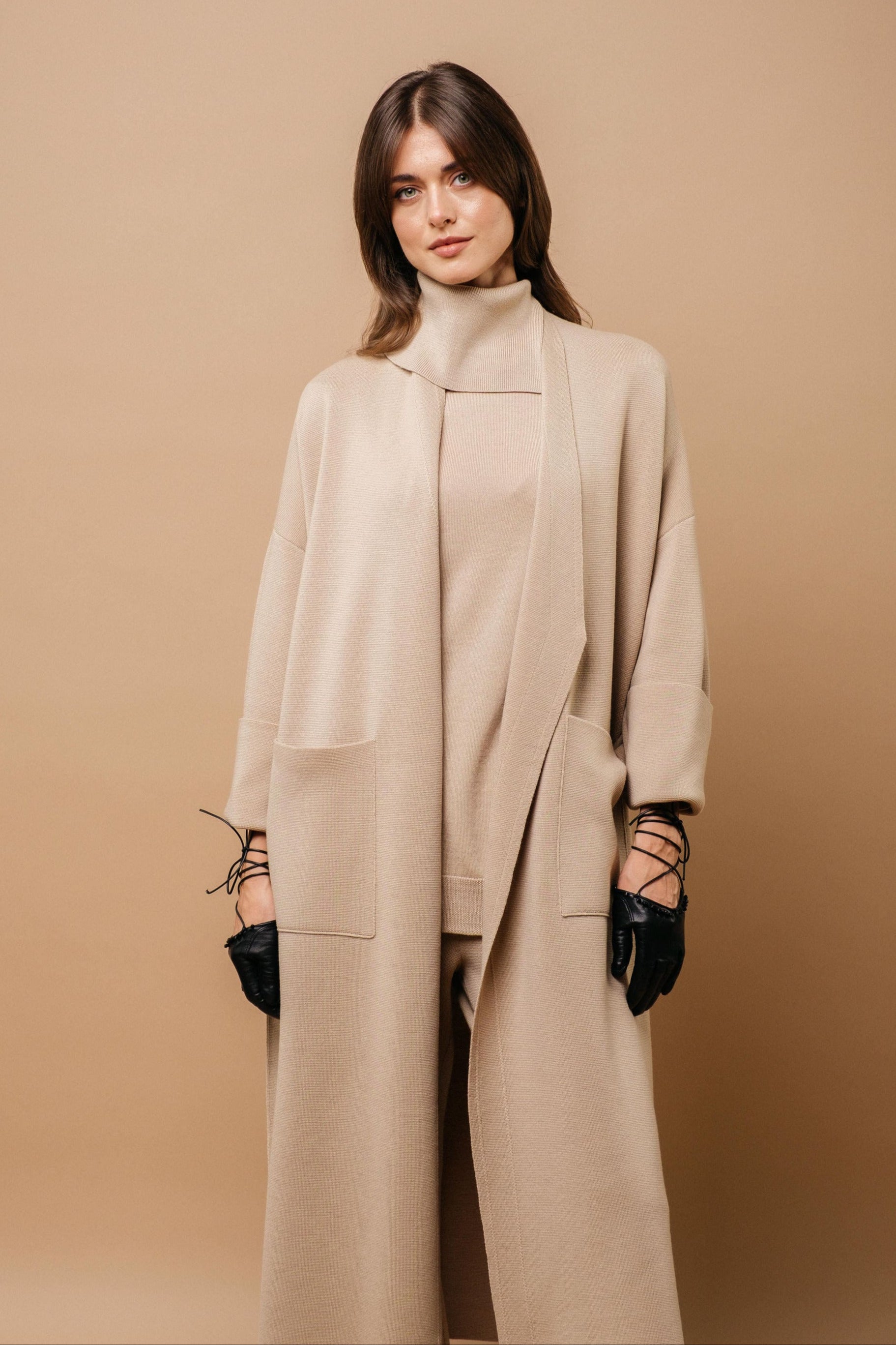Woman wearing a beige coat and gloves against a beige background
