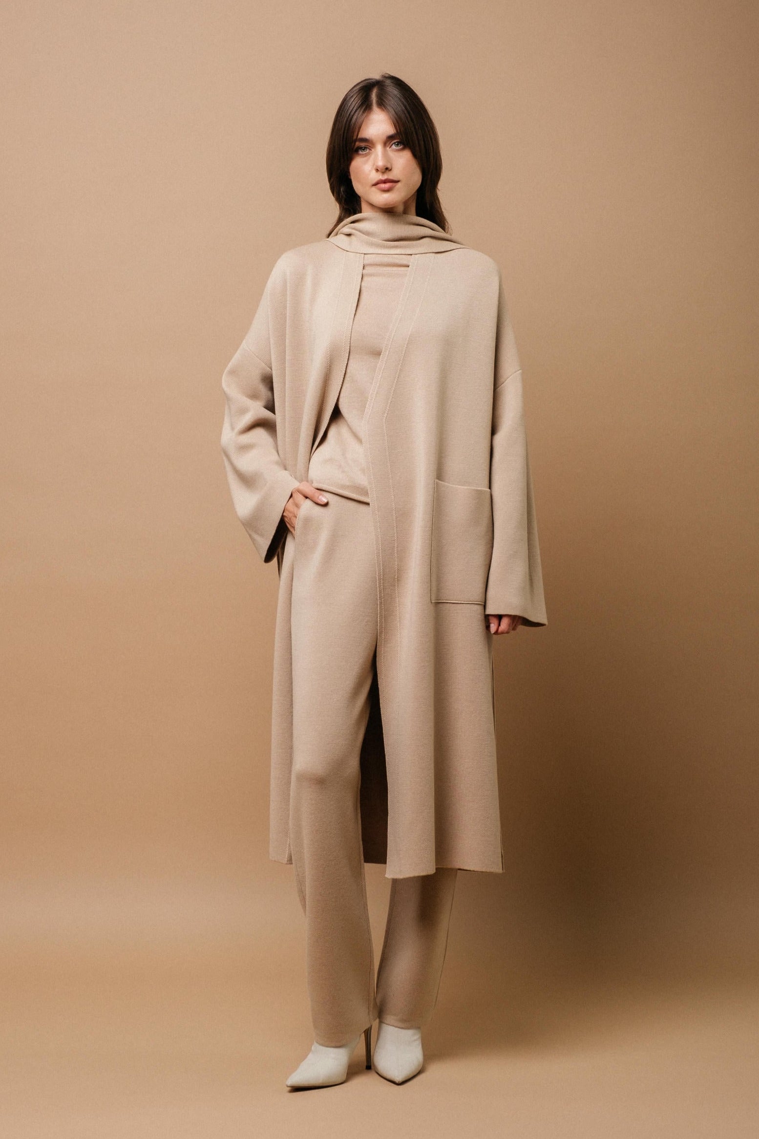 A pink merino wool coat with a belt, designed with wide sleeves and a V-neckline, displayed against a plain background.