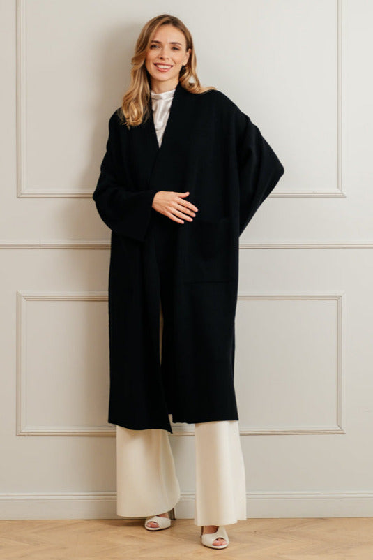 A pink merino wool coat with a belt, designed with wide sleeves and a V-neckline, displayed against a plain background.