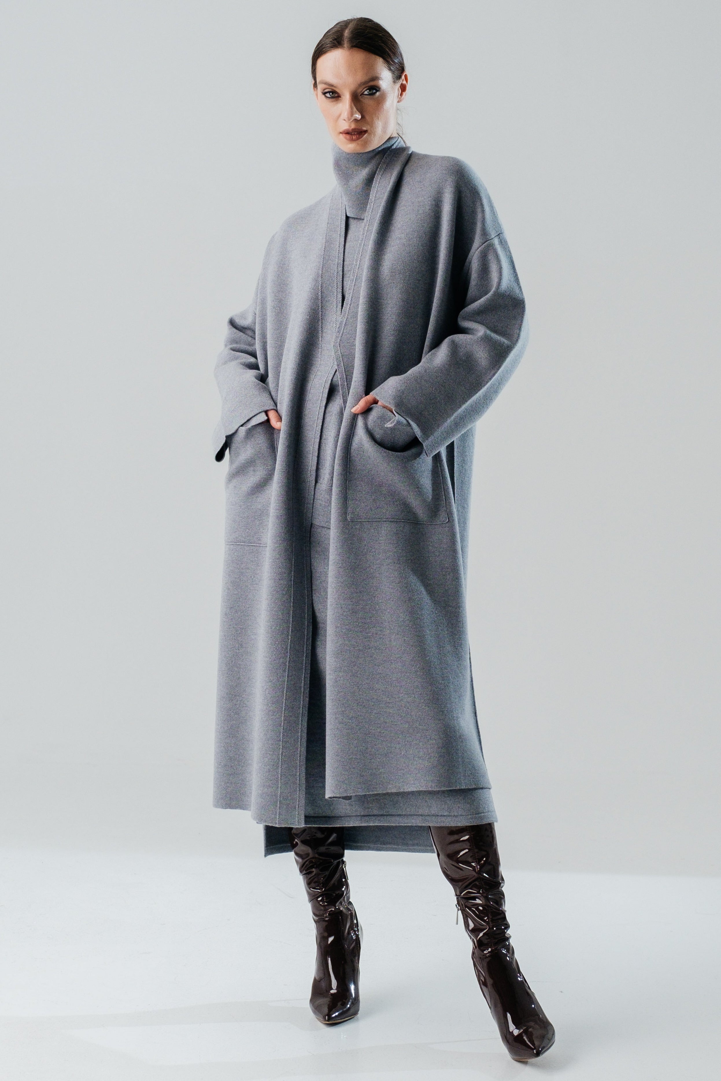 A grey merino wool coat with a belt, designed with wide sleeves and a V-neckline, displayed against a plain background.