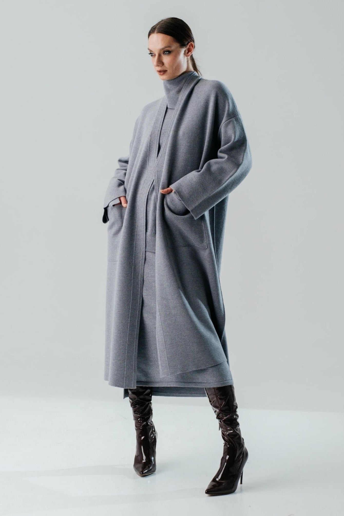 Person wearing a long gray coat on a white background