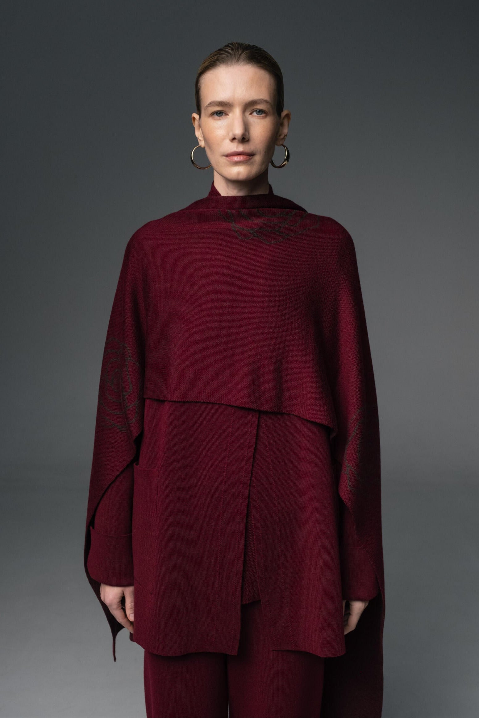 Person wearing a burgundy outfit against a gray background