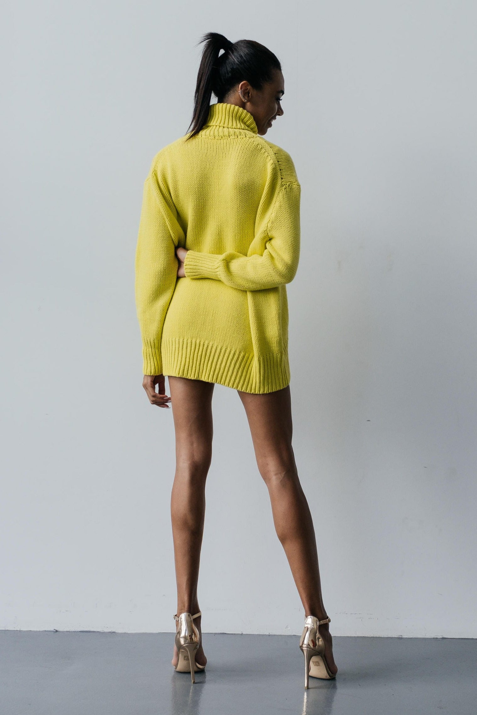 Person wearing a bright yellow sweater and skirt set against a plain background