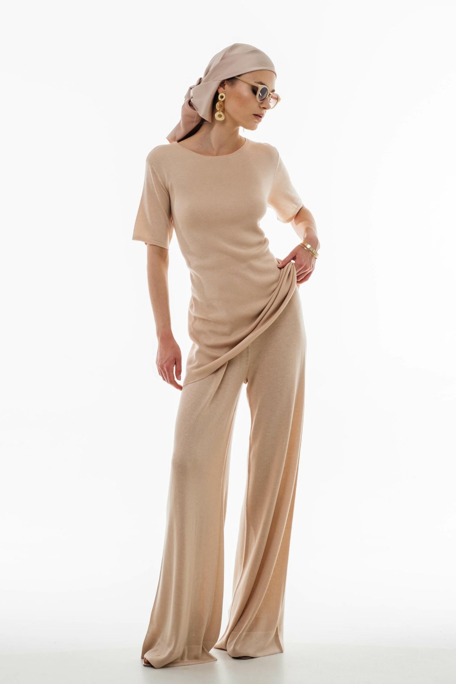 Woman wearing a beige outfit with a draped effect on a white background