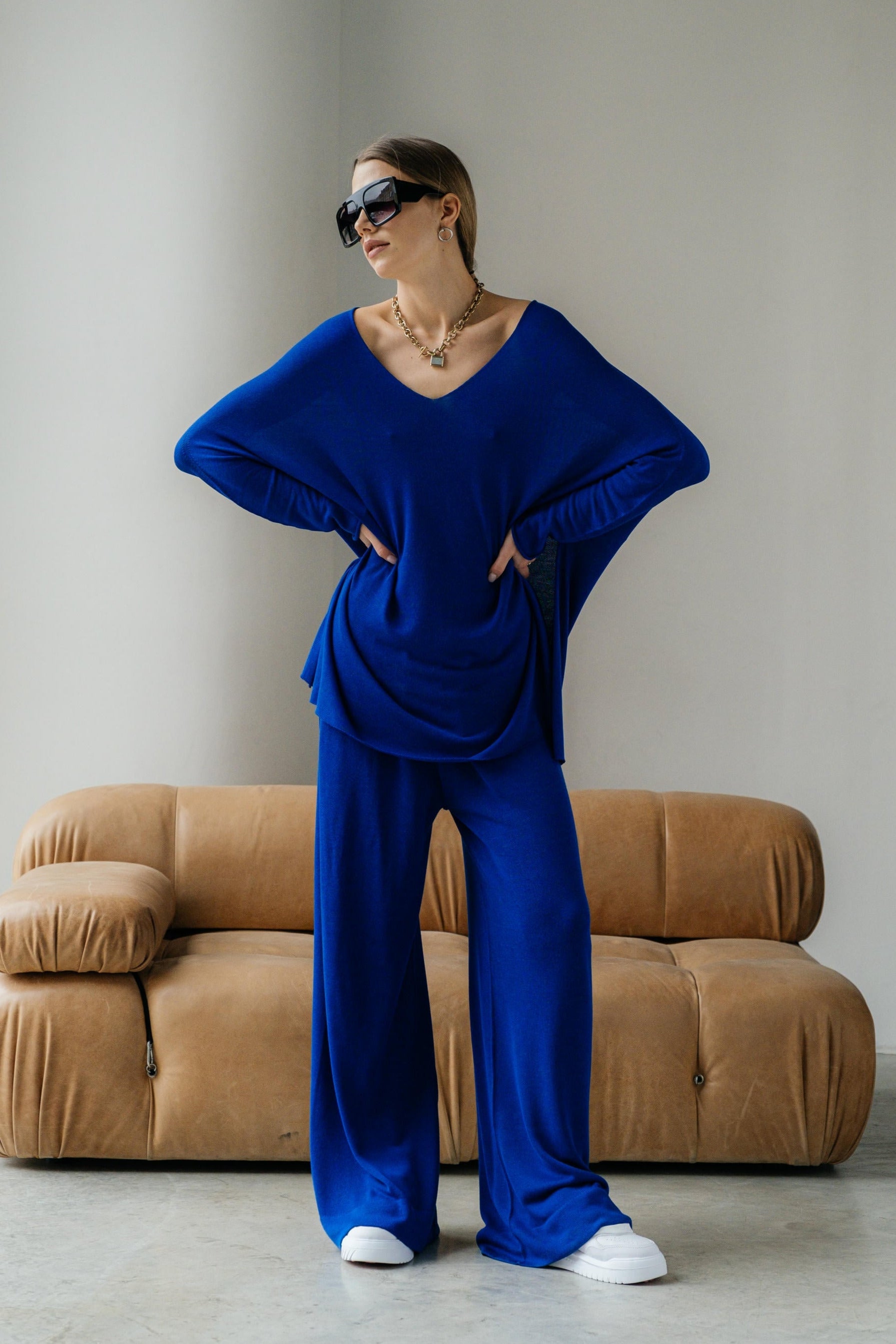 Person wearing a blue outfit standing in front of a beige sofa.