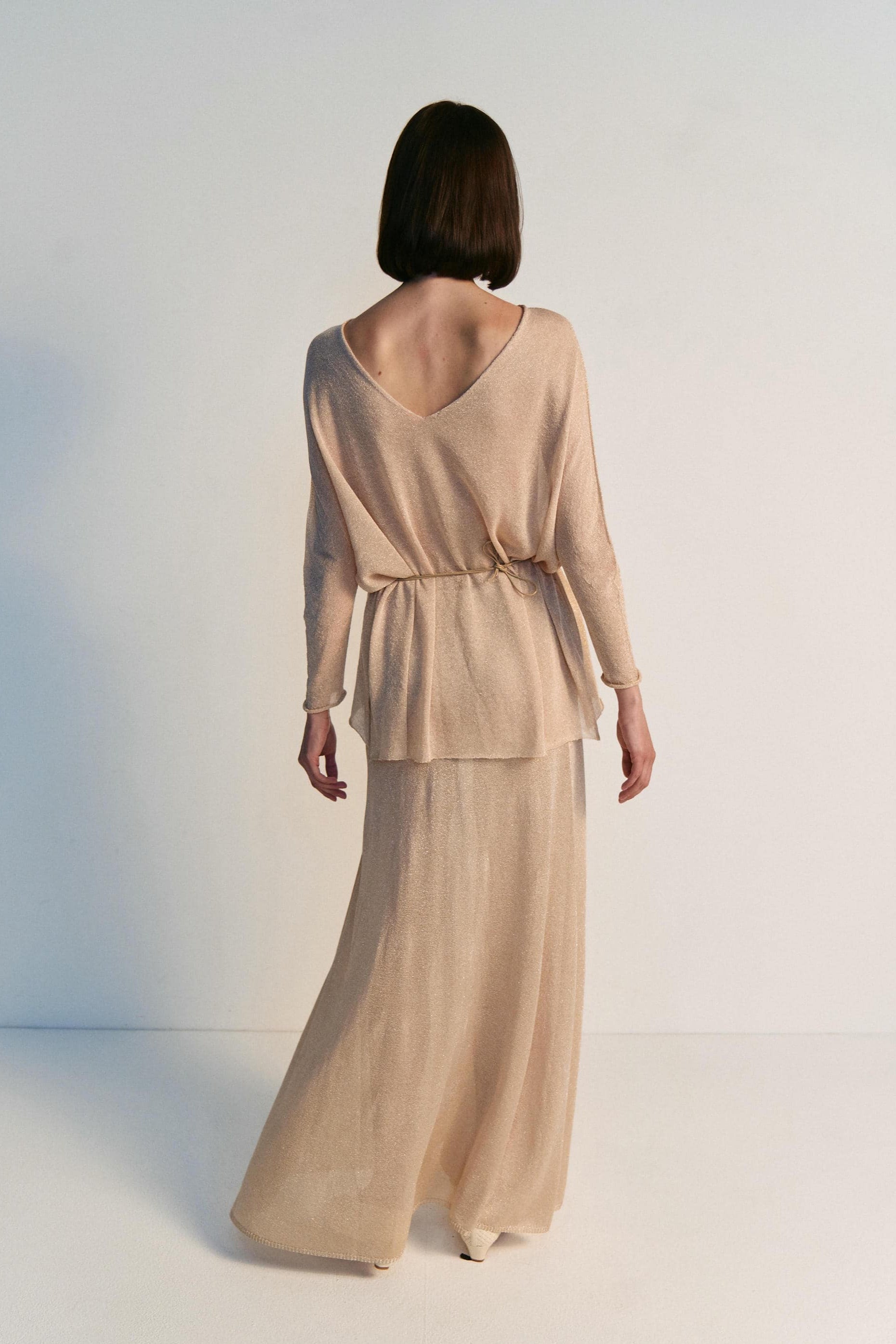 Woman wearing a beige outfit with a plain background