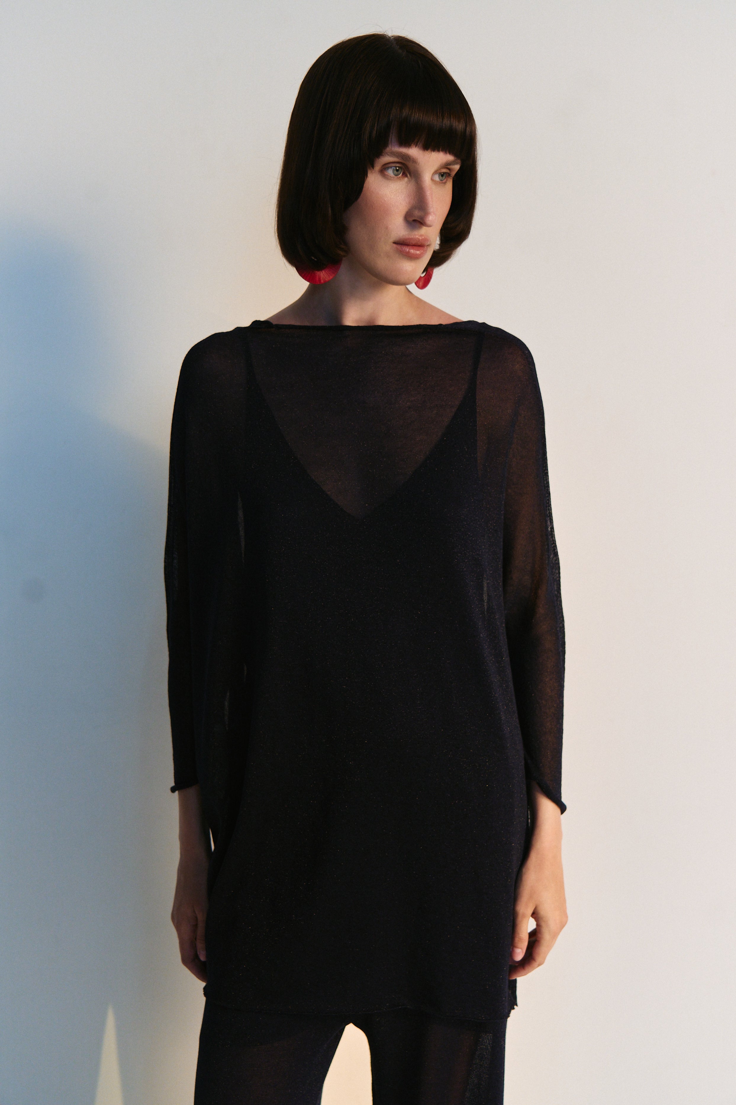 Woman wearing a black dress with sheer back panels against a white background