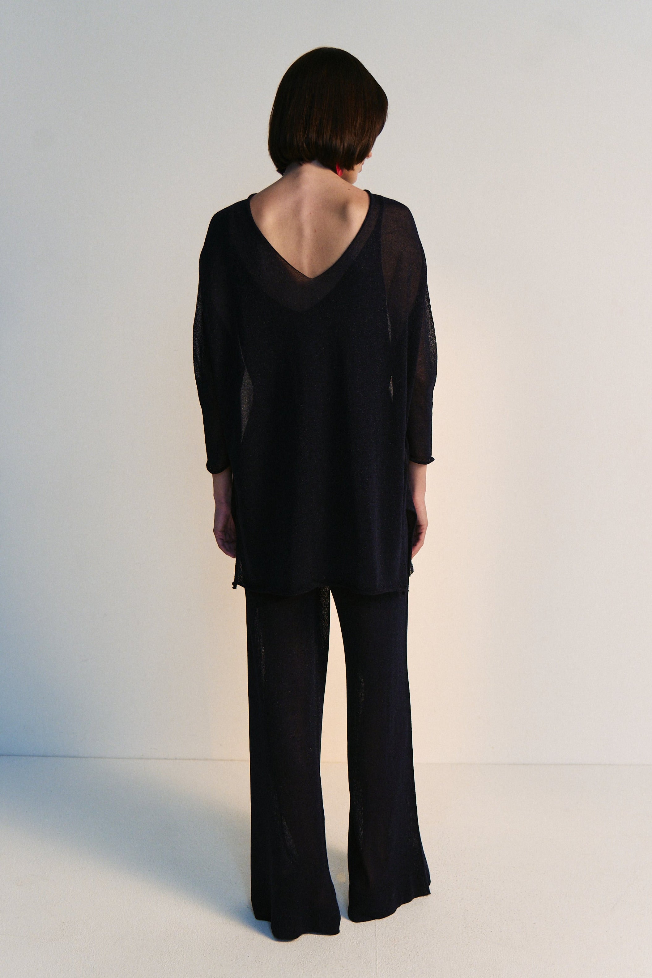 Person wearing a black outfit with a plain background