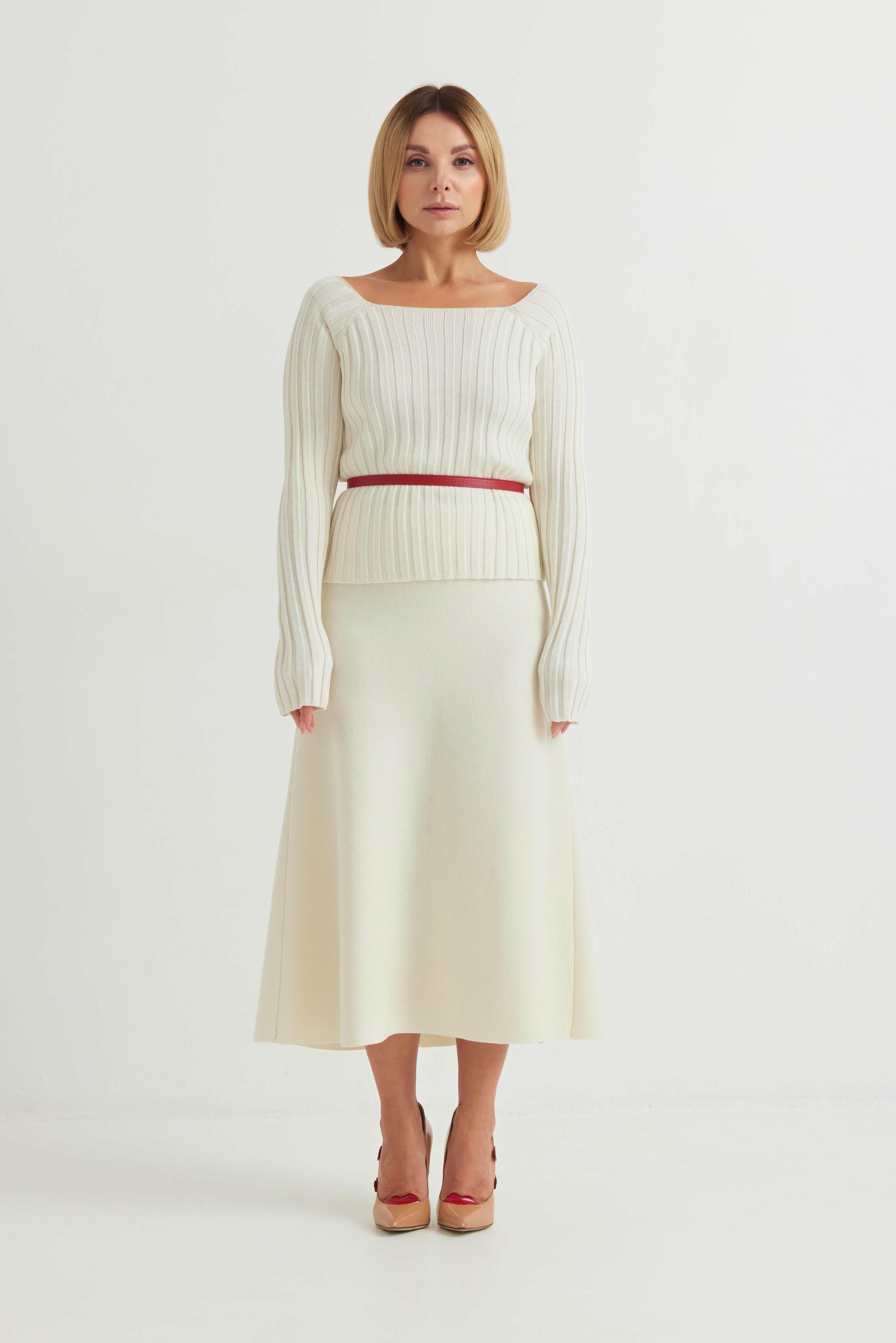 Woman wearing a white ribbed sweater and skirt set on a white background