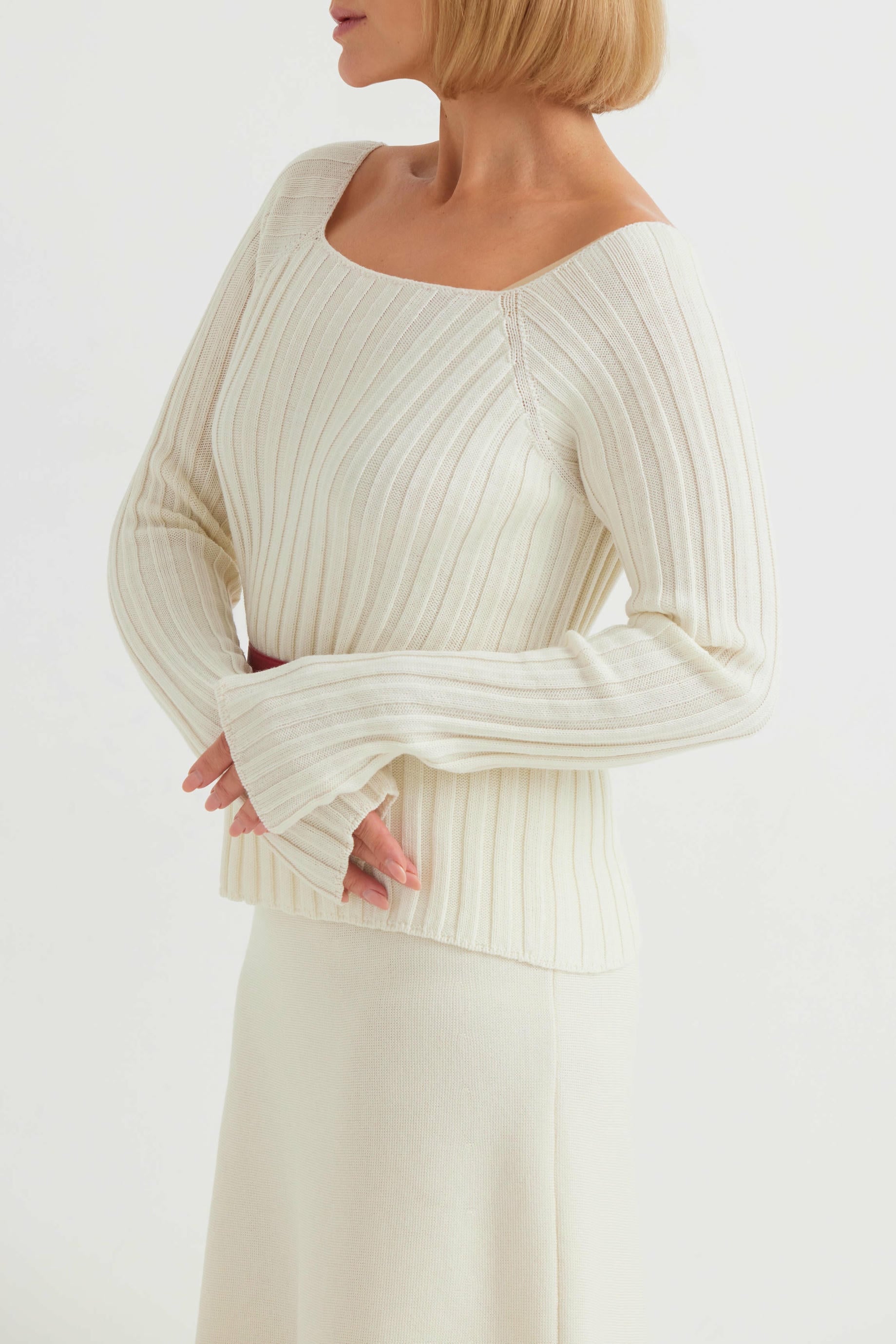 Woman wearing a cream ribbed sweater against a white background