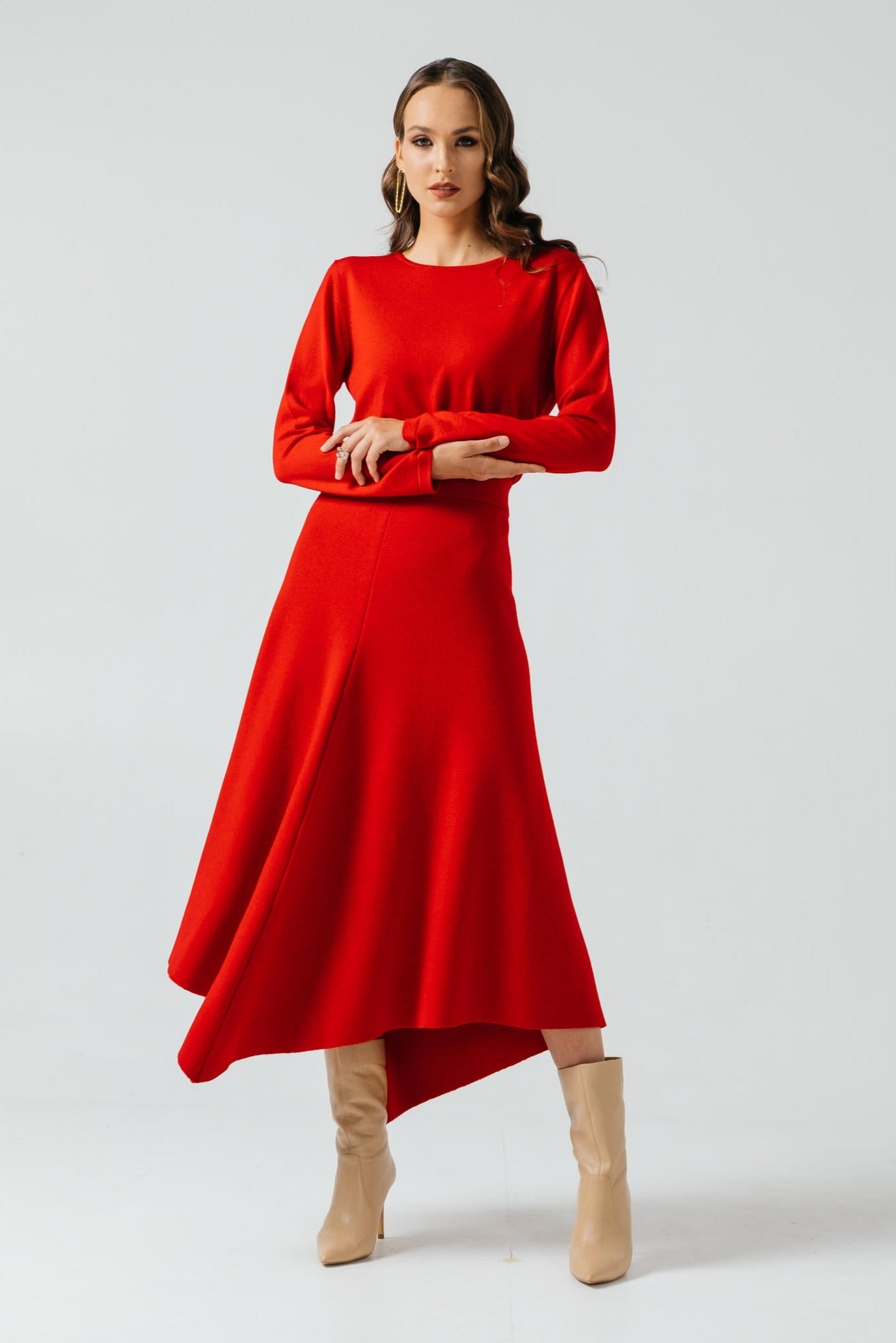 Woman wearing a red dress with beige boots on a white background