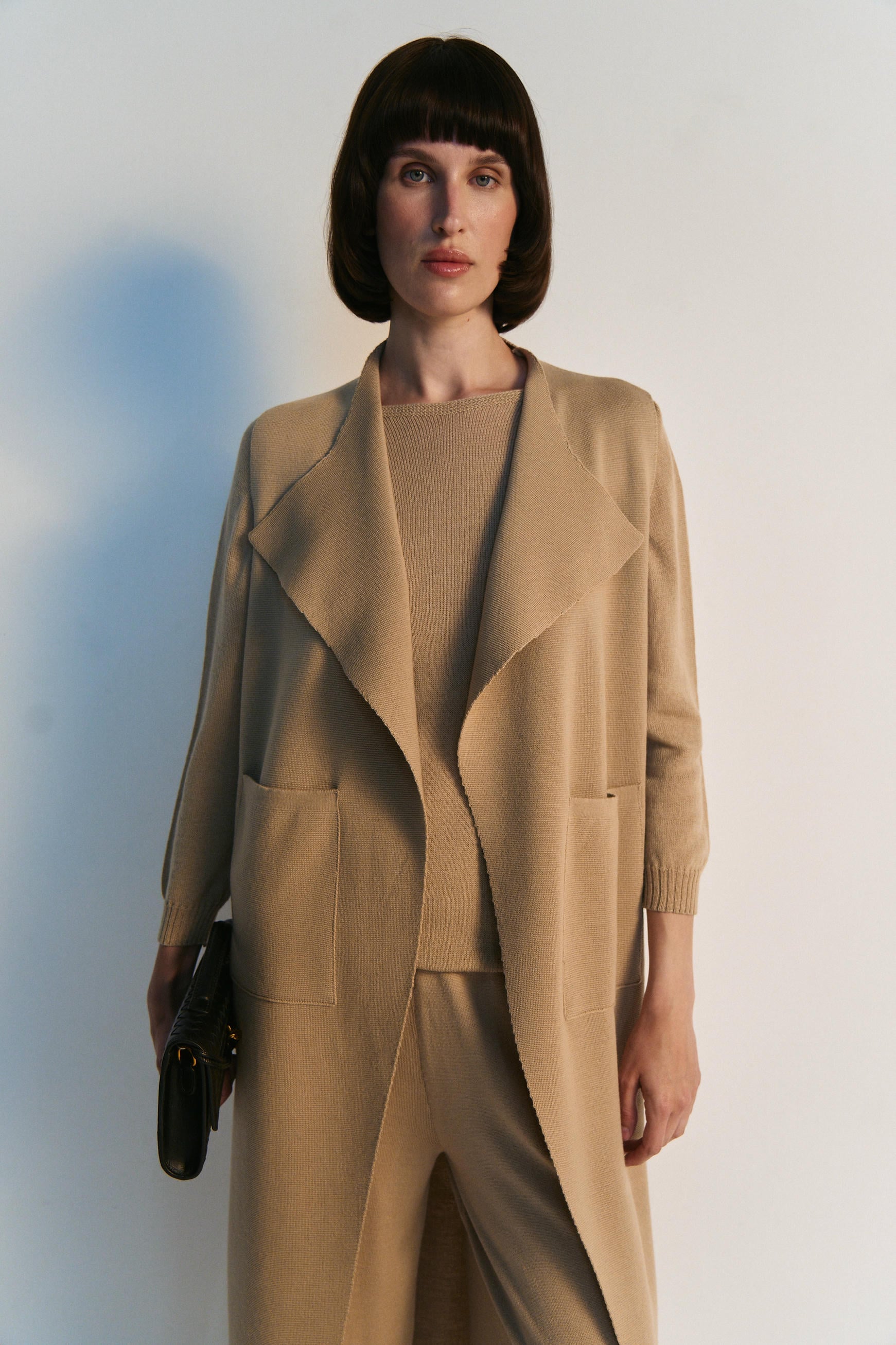 Woman wearing a beige suit with a plain background
