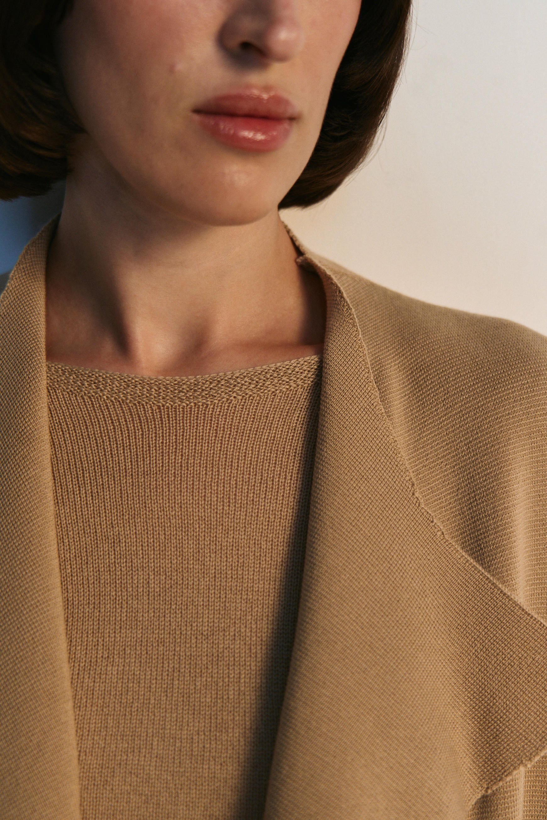 Close-up of a person wearing a brown sweater with a blurred background
