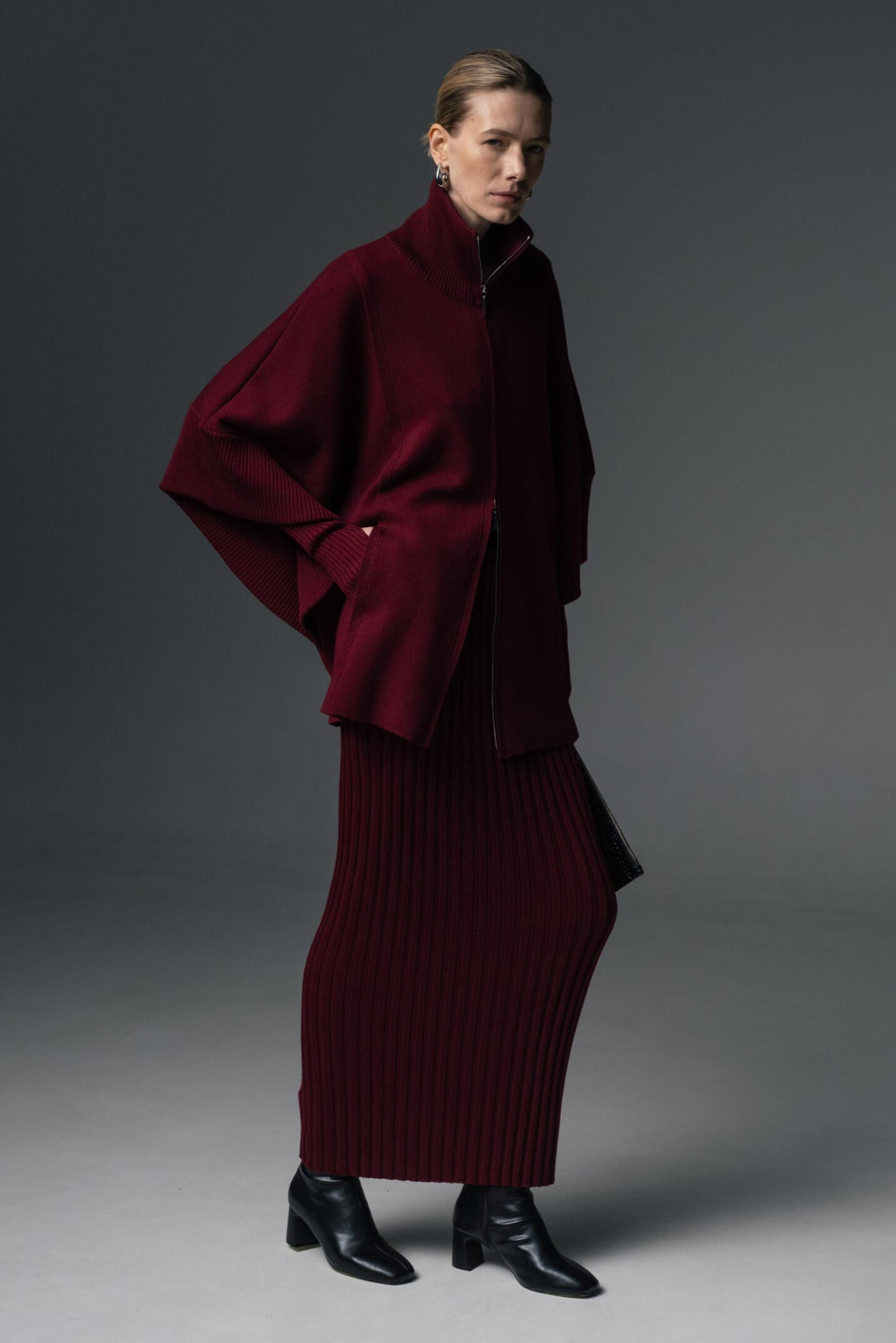Person wearing a burgundy outfit against a gray background