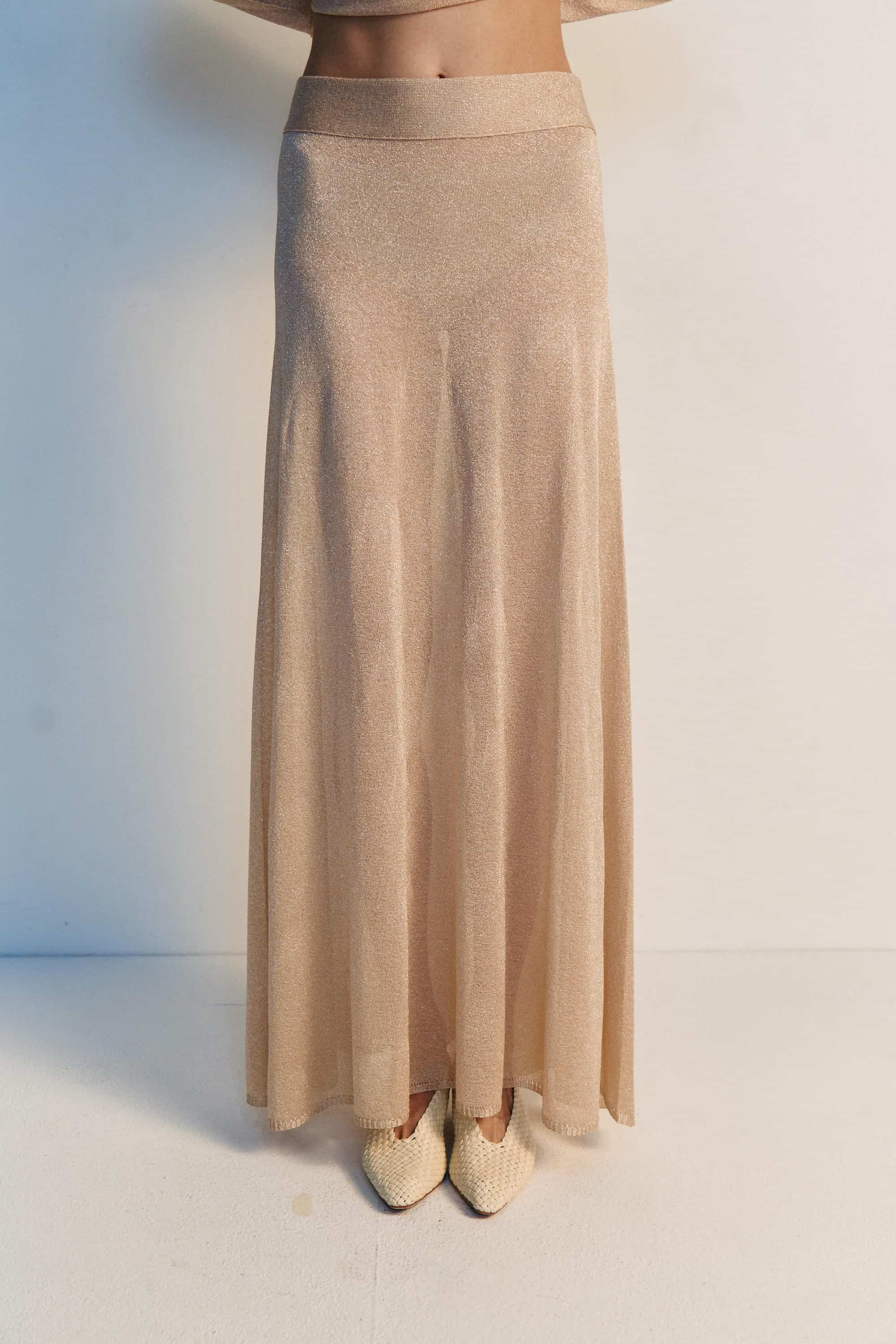 Beige long skirt worn by a person on a white background