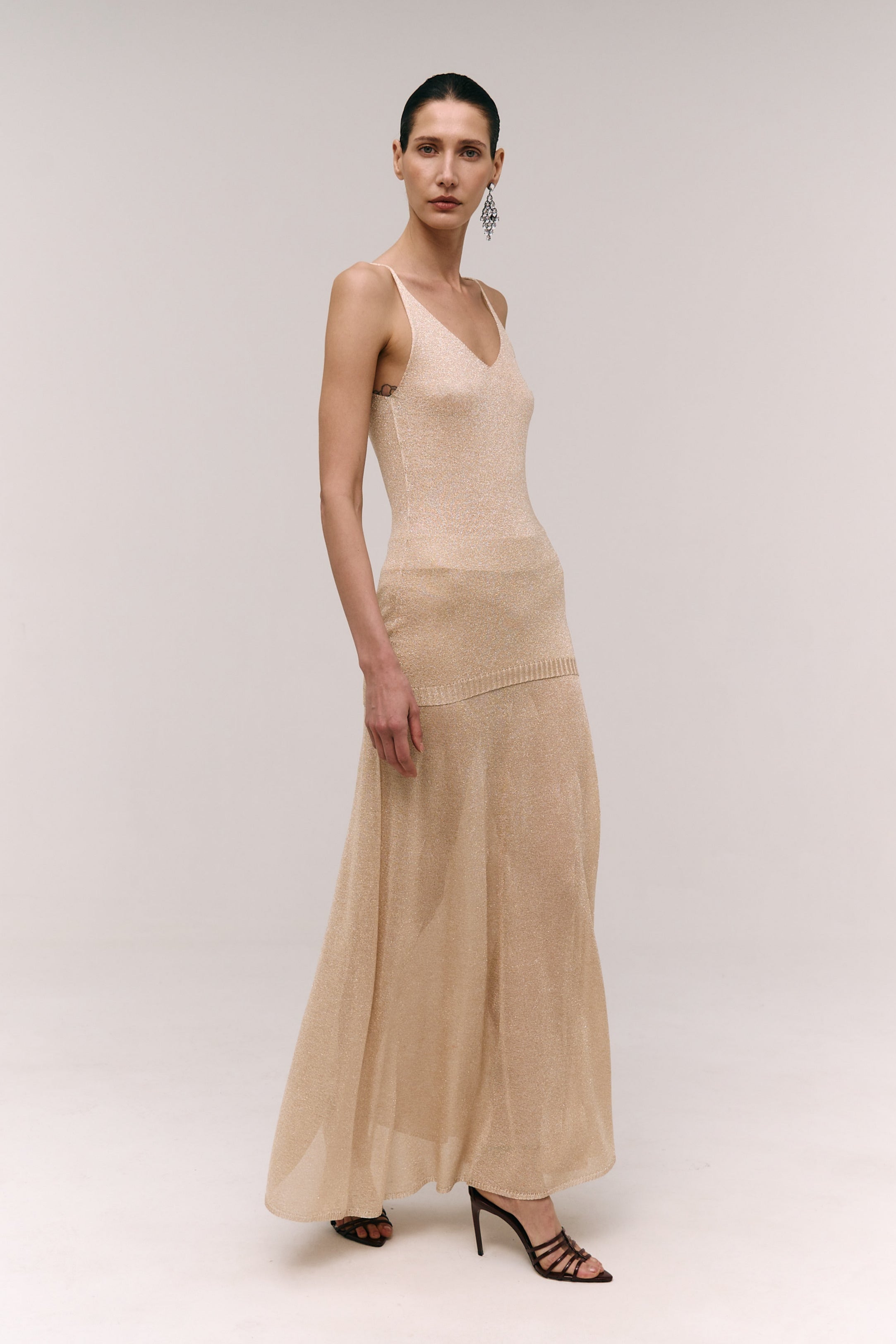 A woman wearing a beige A-line maxi skirt with a ribbed texture and a fluid skirt that extends to the floor.